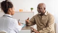 An older man speaking with a physician.